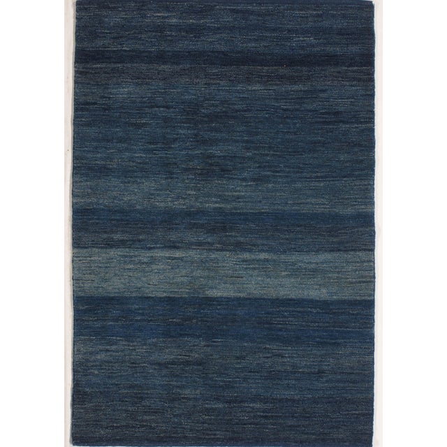 Hand-knotted Persian Lori Gabbeh wool rug with a deep blue field featuring subtle horizontal tonal variation. The...