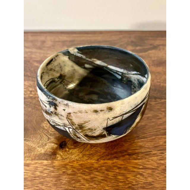 A striking 1984 American studio pottery bowl featuring a complex, painterly glaze in layered whites, deep blues, blacks,...
