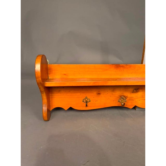 French 19th-century cherry wall-mounted shelf dating to circa 1890, featuring a practical shelf with five bronze hooks and...