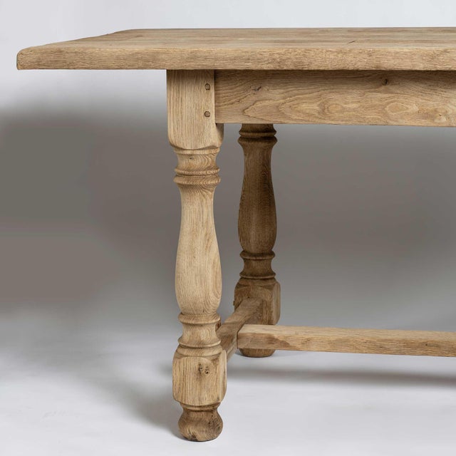 A large bleached oak trestle style table. The table has a single drawer in the center apron on one side. The legs are...