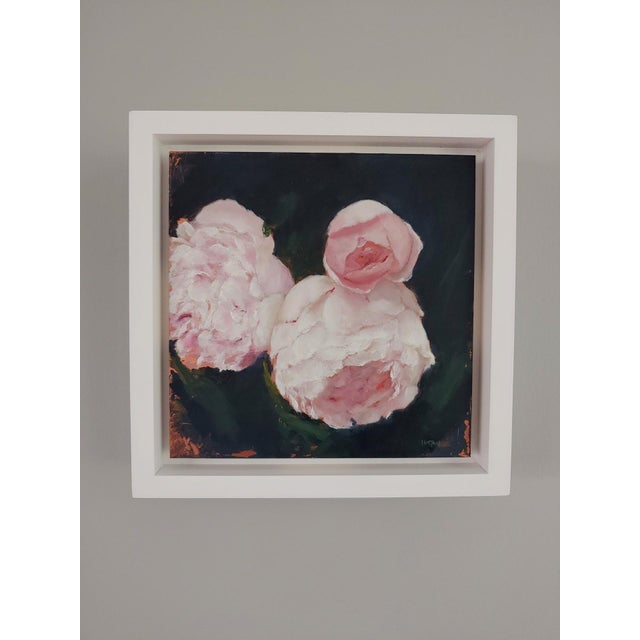 This artwork features a delicate arrangement of spring peonies, rendered in soft pink hues against a deep, contrasting...