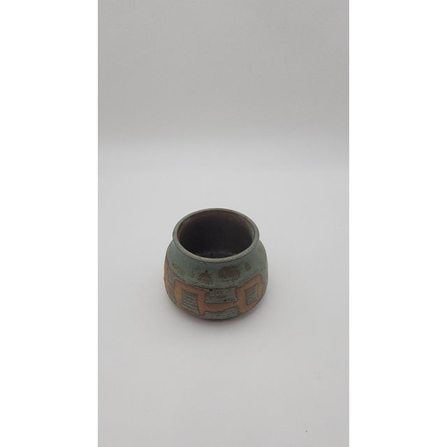 Hand-thrown studio pottery bowl featuring a rounded silhouette with carved geometric motifs in exposed clay beneath a...