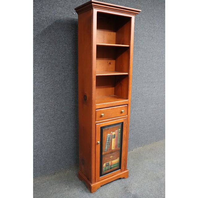Pine chimney cupboard with open shelving above, a small drawer, and a lower cabinet door featuring a hand-painted trompe...