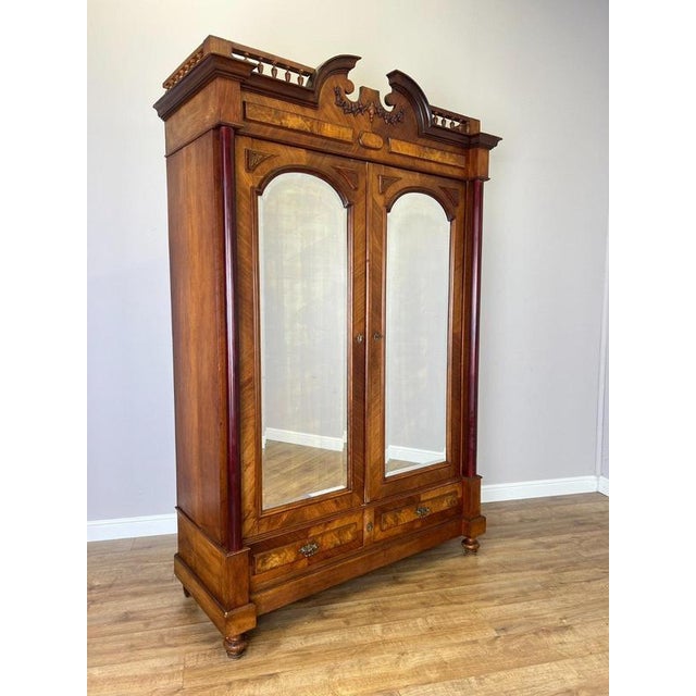 An impressive Antique French wardrobe in Walnut, featuring two tall mirrored doors, decorative inlaid detailing, turned...