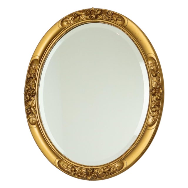 French oval gold mirror featuring rose ornamentation and a beaded border; the frame is made of wood and the glass is...