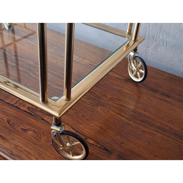 High quality Hollywood Regency bart cart / drinks trolley in gilt brass with 2 glass tiers and a rack for bottles.