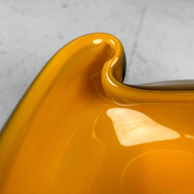 Beautiful mouth-blown glass bowl with an organic design. The bowl features a warm yellow/orange color and dates back to...