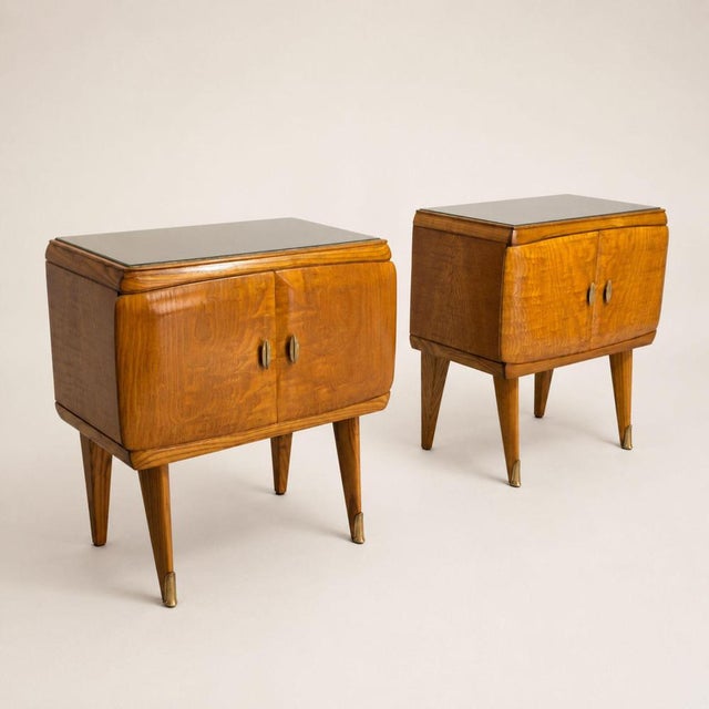 A pair of 1960s Italian Midcentury Modern bedside tables, crafted from birch with brass accents and a glass top. The...