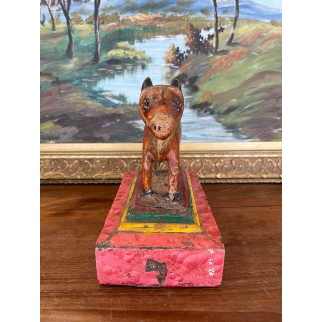 Likely Early 20th-century hand-carved wooden cow figurine mounted on a rectangular painted base. The cow is carved from...
