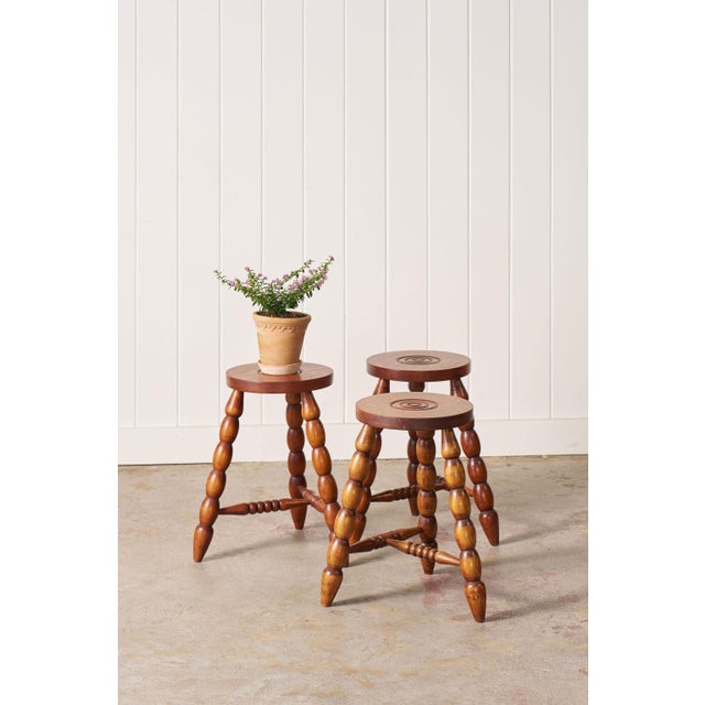 Antique French bobbin stool with a circular seat, turned bobbin legs, and an H-form stretcher, crafted from solid wood...
