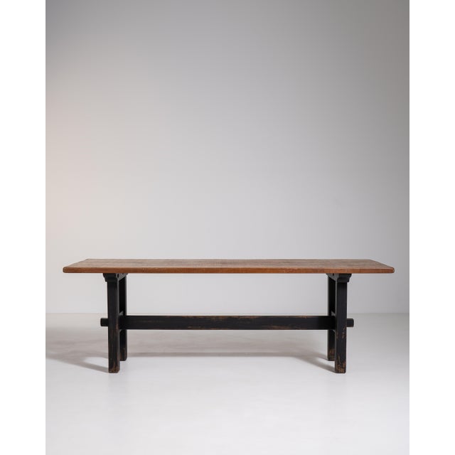 A distinctive oak dining table featuring contrasting black patinated legs that enhance its visual presence. The natural...
