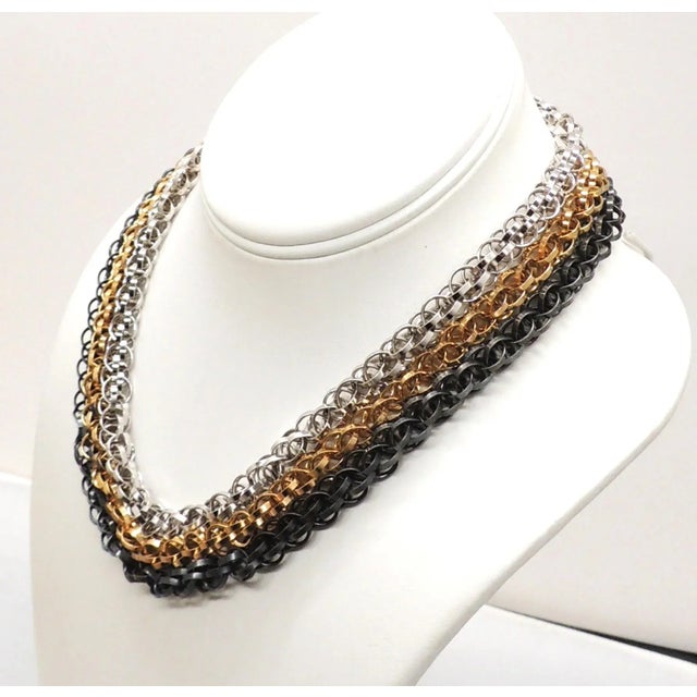 This is part of Chairish’s Costume Jewelry assortment. 3-strand goldtone, rhodium plate and blackened metal interlocking...
