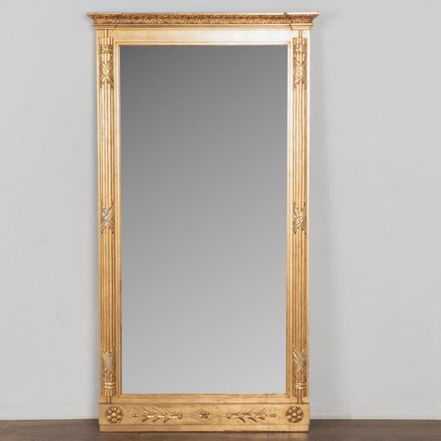 Early 19th century Swedish neoclassical mirror crafted in giltwood. The frame features a burnished gold gilt finish with a...