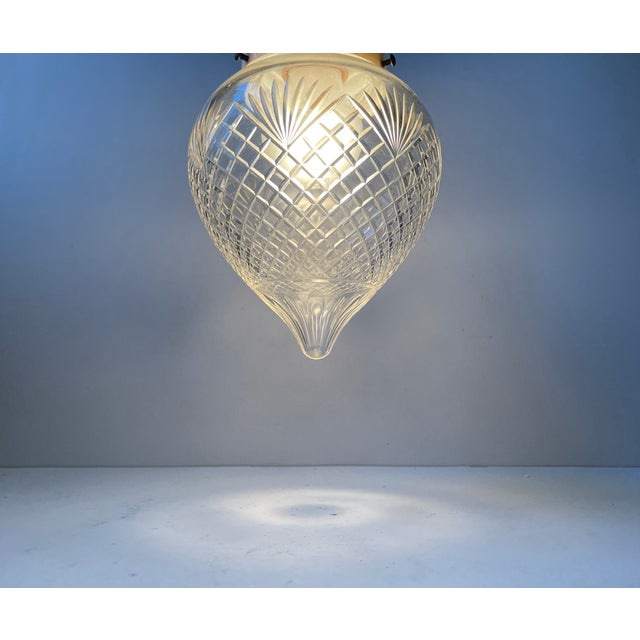 A 1920s drop shaped crystal pendant cut with geometric and floral patterns. It comes in a white bakelite socket and with...