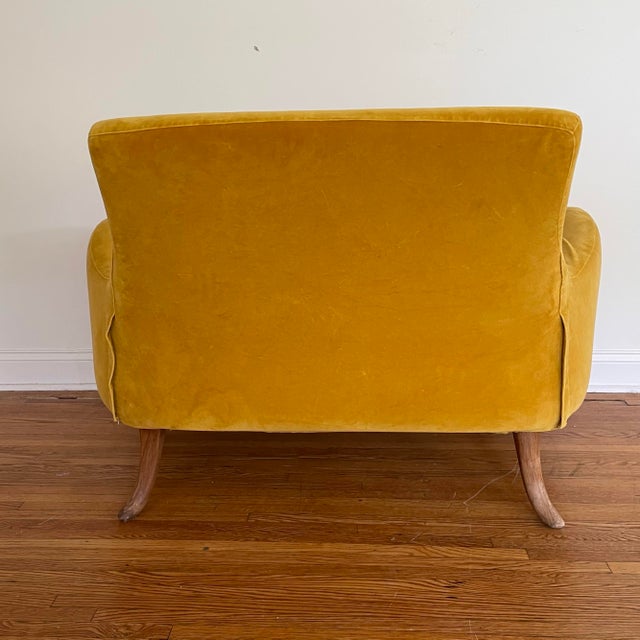 A vintage 1960’s loveseat. The chair features a curvaceous profile with swooping sheltering armrests and a pitched...