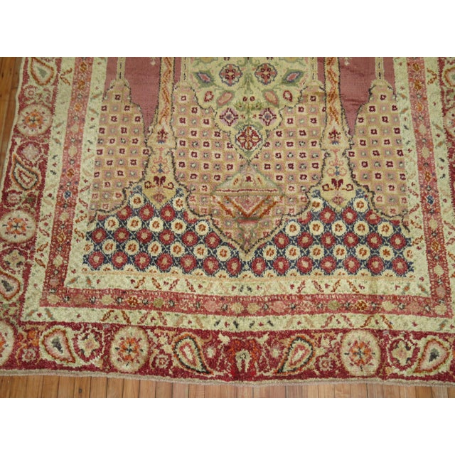 an early 20th-century intermediate-size Turkish Ghiordes rug with a scroll prayer niche design commonly found in smaller...