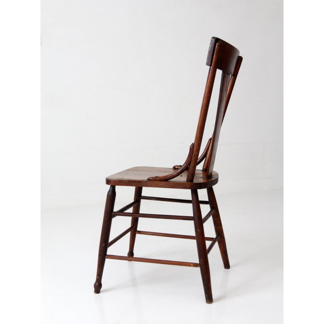 A 19th century American splat back chair featuring a warm aged wood finish and classic farmhouse form. The chair is...