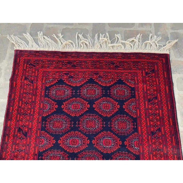 Add a touch of tradition and elegance to your home with this hand-knotted wool rug, featuring a striking navy and red...