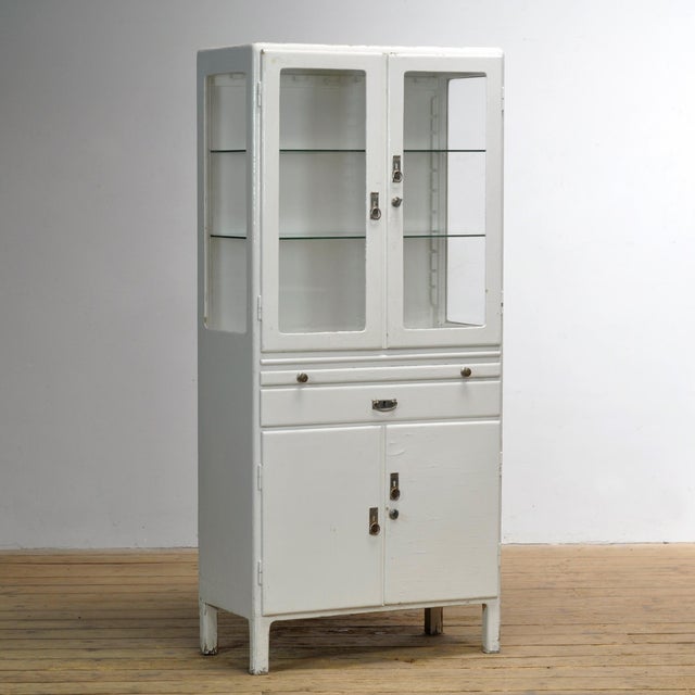 This wooden medical cabinet from the 1950s combines functionality with timeless charm. The upper section features two...