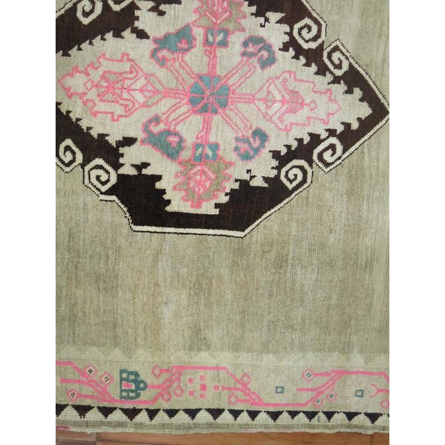 A very unique Turkish Kars rug with four striking medallions in brown and pink surrounded by a wavy pink motif border....