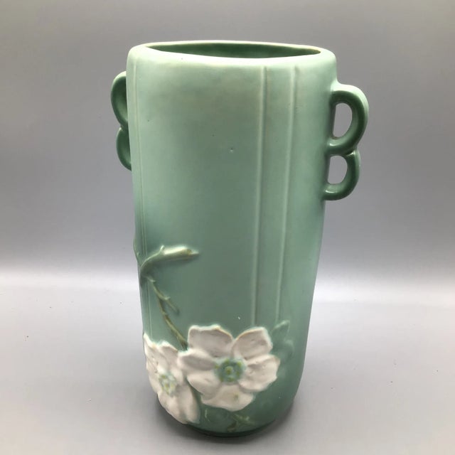 This Weller Pottery Wild rose vase in a green matted finish has double loop handles on each side with the rose stems...