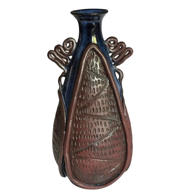 Unique studio pottery vase with beautiful glazed blue and detailed brown clay detail on top. Measuring 8” x 4”, this can...