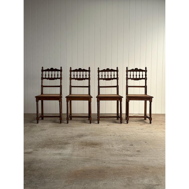 Antique dining chairs with turned spindle backs and carved rosette crest detail. Framed cane seats supported by turned...