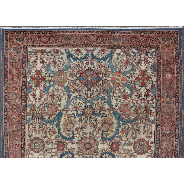 Antique Persian Sultanabad Rug in Ivory Background, Blue, Salmon & Multi Colors. This antique Sultanabad rug features a...