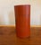 A striking vintage Japanese tea canister featuring a vivid red lacquer finish adorned with a hand-painted landscape of...