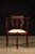 American turn-of-the-century mahogany arm chair with padded and upholstered oval seat panel. This antique piece features...