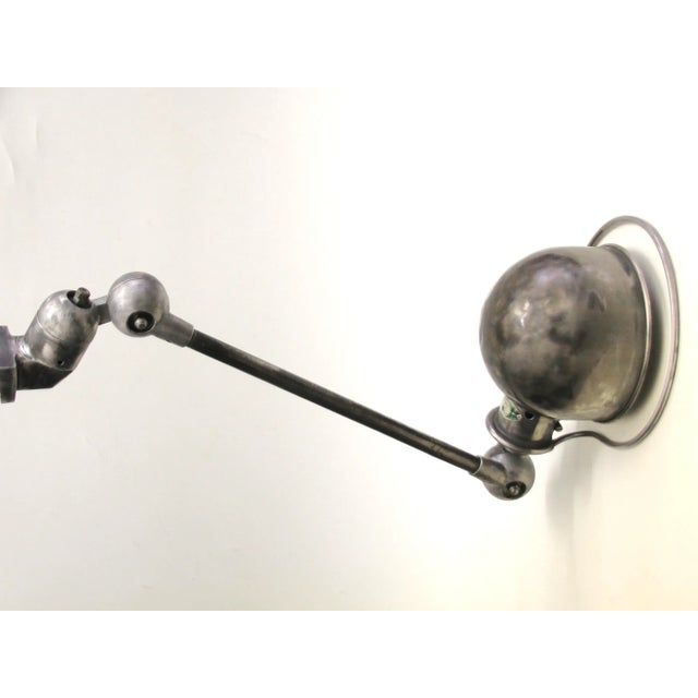 This industrial wall lamp was designed by Jean-Louis Domecq and manufactured in the 1950s. The vintage metal lamp is in a...