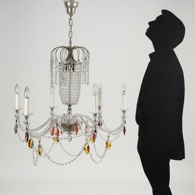 Six-light chandelier, adorned with glass and colored glass necklaces and pendants. This piece is attributed to the...