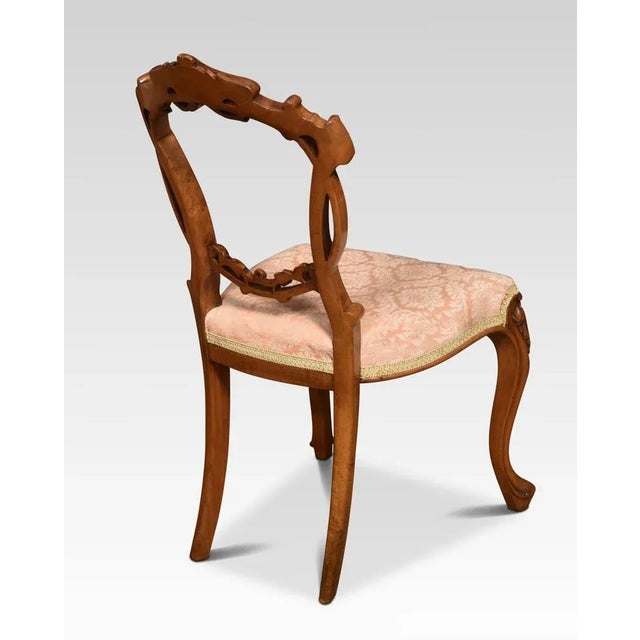 Set of four walnut balloon back dining chairs, each chair with an openwork ring back interlaced with carved scrolling...