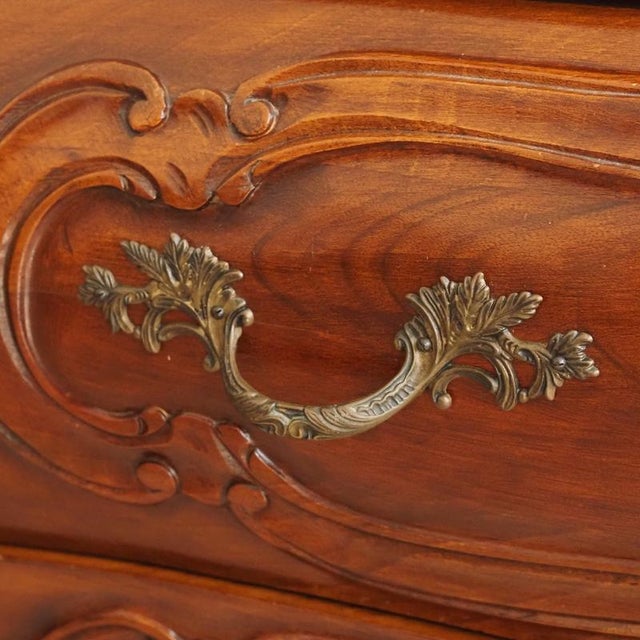 A bombé commode in the baroque/rococo style, crafted around 1900 from solid walnut. The curved bombé shape with its three-...