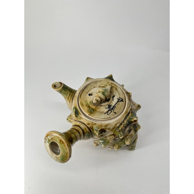 A rare and charming vintage Japanese teapot crafted in the unique shape of a conch shell (sazae). This exquisite piece...