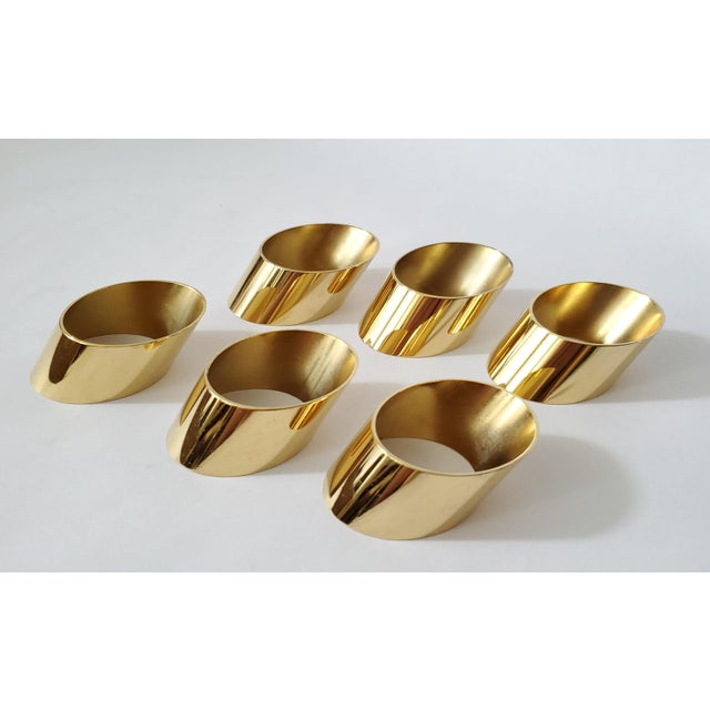 Offering a luxurious set of 24 karat gold plated Mid 20th Century Modern napkin rings, circa 1960s. The angled shaped oval...