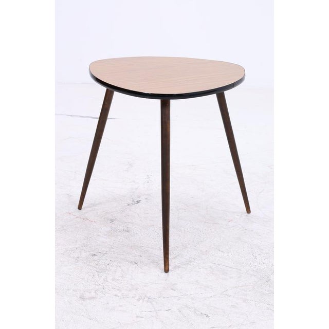 Vintage side table in a classic mid-century design with slender, tapered legs. The characteristic organic shape and warm...