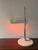 A distinctive space-age desk lamp, likely from the 1970s. It features a rectangular, slotted metal shade, a slender chrome...