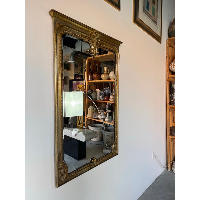 A glamorous 1970s vintage Italian wall mirror in the Hollywood Regency style, featuring a hand-carved wood frame finished...
