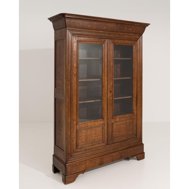 A French oak vitrine dating to the late 19th century. The cabinet features glass-front doors and a simple, well-balanced...