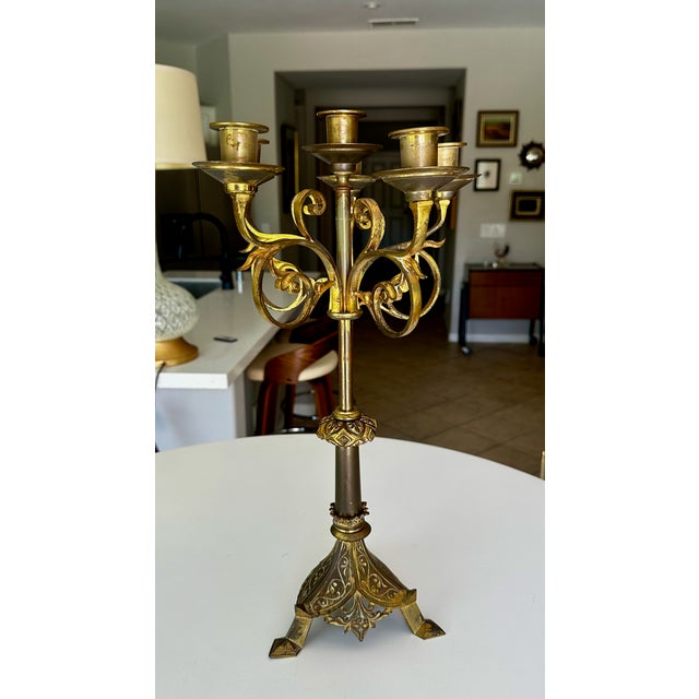 Single 1920s Gothic Revival brass candelabra featuring a six-light branch configuration and an ornate tri-form footed base.