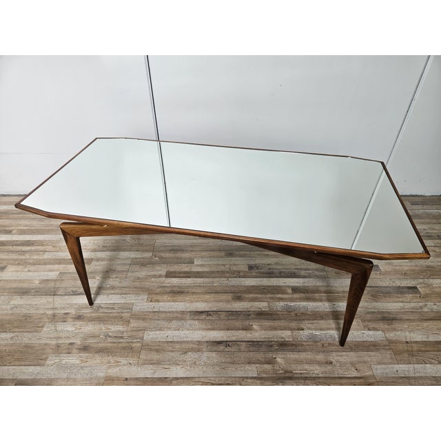 An elegant mid-twentieth-century vintage dining table, featuring a refined wooden frame with sinuous, sculptural lines,...