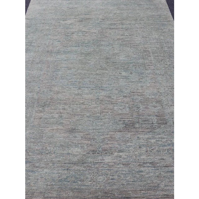 Measures: 6'0 x 9'3. This modern Indian rug has been hand-knotted in wool and features an all-over, sub-geometric design...