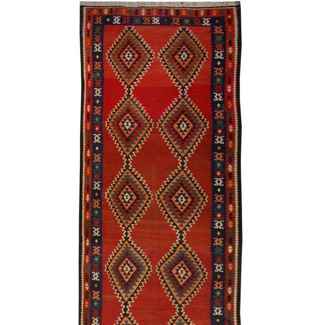 An early 20th Century Persian Kilim runner with multiple multicolored diamond medallions on a variegated crimson...