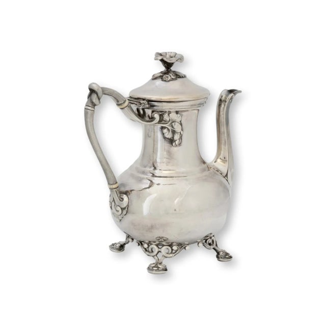 An elegant antique silver-plated coffee pot by Christofle, showcasing ornate Rococo details including a floral finial,...