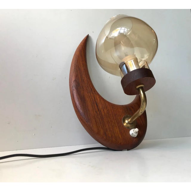 Moon shaped fixed wall light composed of solid teak, brass and smoke glass. Made from excess furniture wood during the...