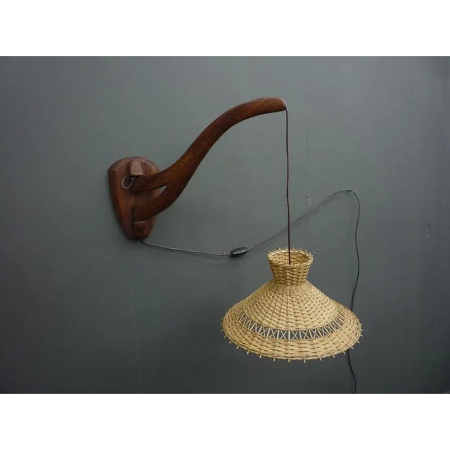 Very rare teak wall lamp from Denmark. The wall mount was made of solid teak. The lampshade is made of wicker. The wall...
