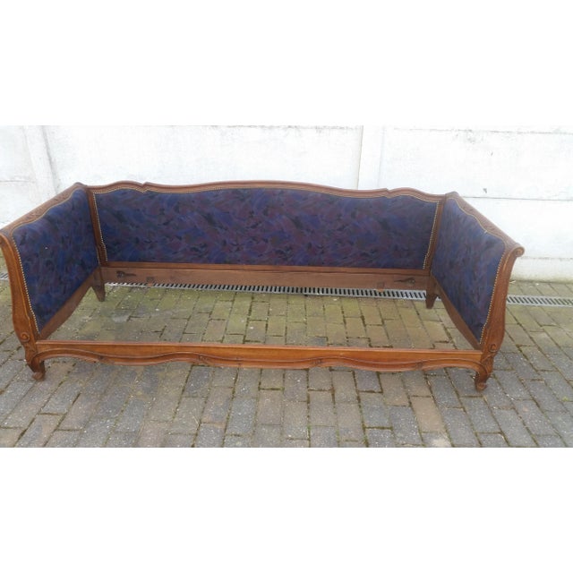 This antique daybed features walnut wood and has been reupholstered.