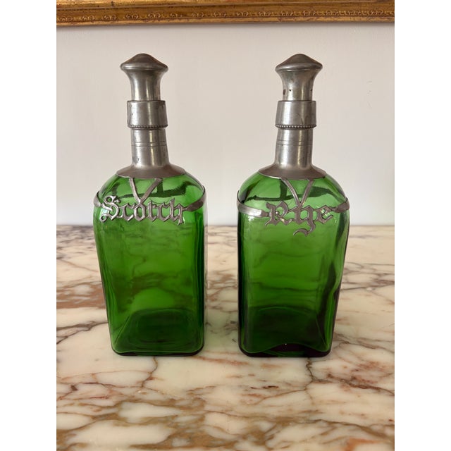 Lovely pair of vintage green decanters with pewter cages labeled in gothic style font. One labeled “Rye” and the other...