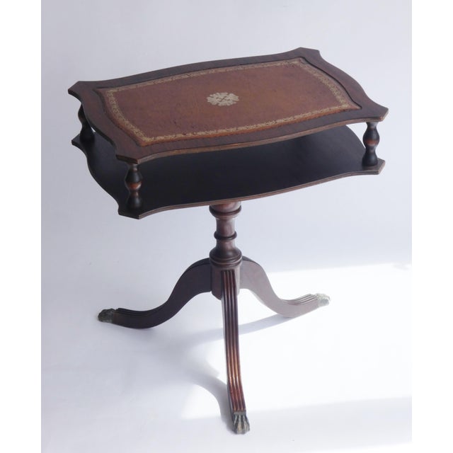 An antique Victorian rectangular wooden table with a brown leather top and a space in the middle. The nightstand is...